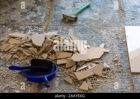 Home renovation close up of broken ceramic tiles in an entrance way. Breaking up the tiles DIY and cleaning up broken pieces before laying new tiles w Stock Photo