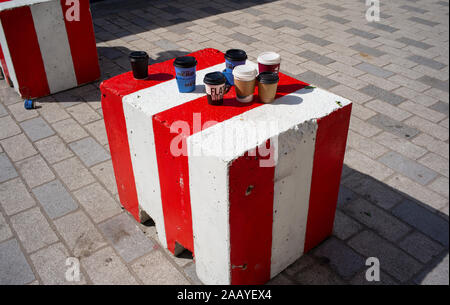 An assortment of one use disposable coffee cups left on concrete block in a street in London England Stock Photo