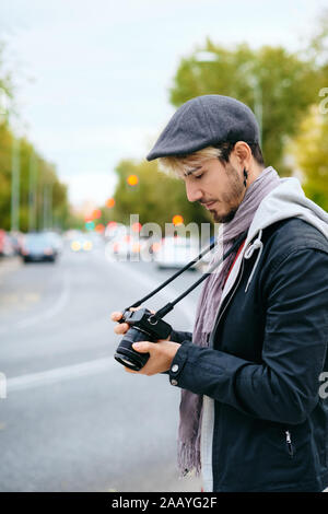 Hipster Street Photographer Reviewing Pictures On Mirrorless Camera Display Stock Photo