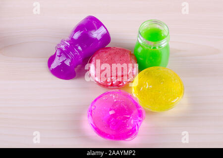 Bright multi colored slimes on a table. Kids most popular toy of nowadays. Slime in plastic containers. Stock Photo