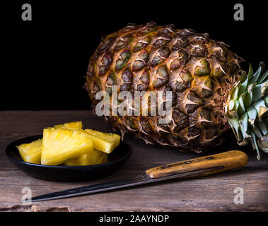 Sliced pineapple on old rustic desk Black background. Stock Photo