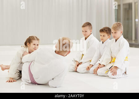 Coach teaching the group of children they practicing in karate on the floor in the gym Stock Photo