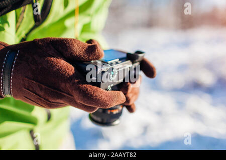 Man setting up camera. Photographer takes pictures of winter forest landscape. Stock Photo