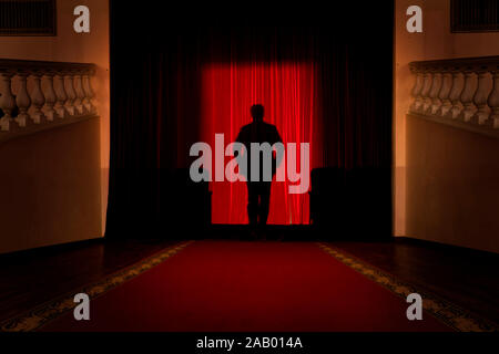 A silhouette of a man against a red curtain Stock Photo