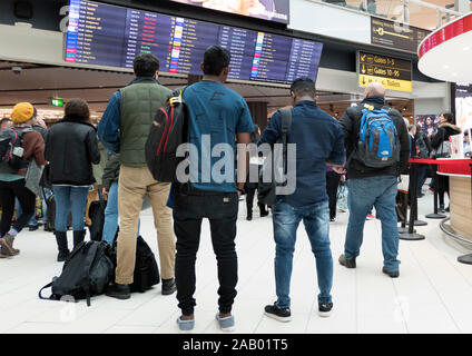 Passengers look at flight departures board Gatwick Airport London UK Stock Photo