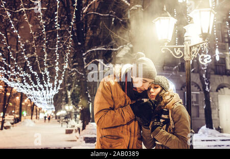 Young couple drinking hot tea in the city center under illumination Stock Photo