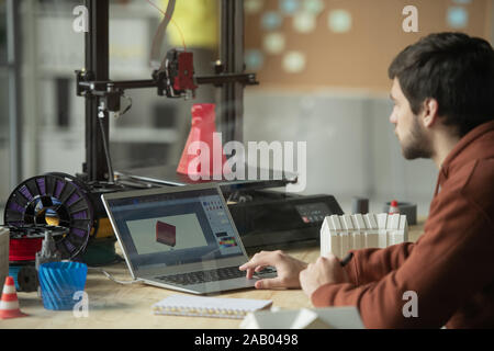 Young creative engineer or designer working over picture of new 3d model in laptop before printing it Stock Photo