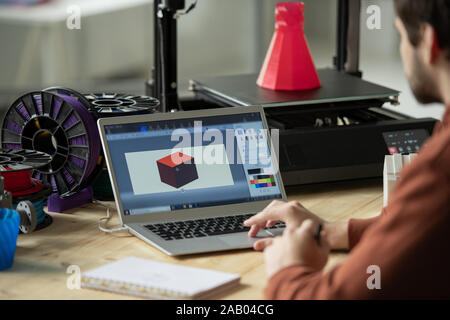 Creative designer working over new 3d model on laptop screen before printing it on special equipment in office Stock Photo
