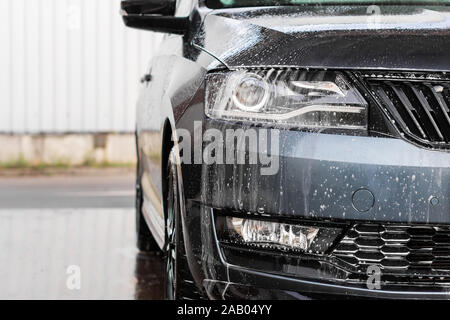 Water drops and foam on the car light in the vehcle wash station. Cleaning automobile concept, underground water pollution. Stock Photo