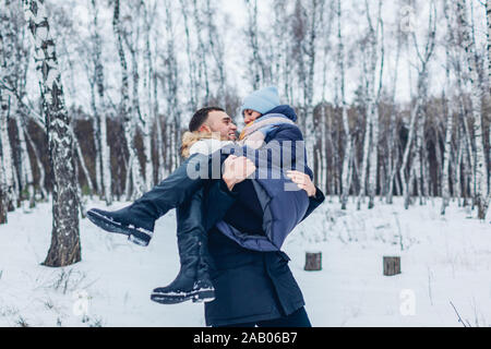 Man carrying his girlfriend on hands in winter forest. People having fun outdoors. Couple relaxing Stock Photo