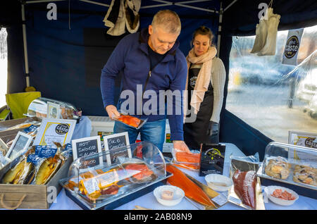 Fishmonger stallholders with display of Nobles award winning cured fish and shellfish for sale in Saltburn Farmers Market in Autumn with 2019 prices Stock Photo
