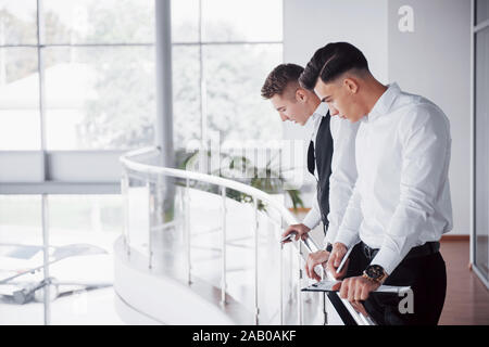 Young business people looking at documents and products standing at the office railing Stock Photo