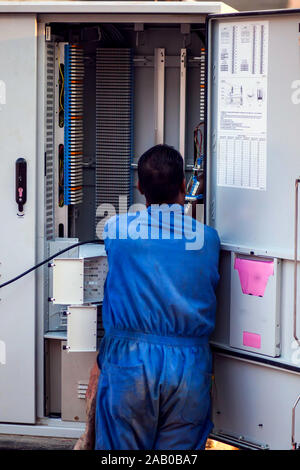 Electrician worker in blue work clothes checking transformation box on the street Stock Photo