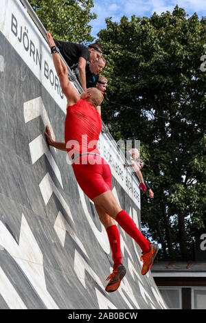 Man in red outfit trying to conquer an obstacle at Though Viking race 2019 in Helsinki, Finland Stock Photo