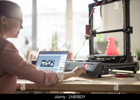 Creative female designer pushing button on control panel of 3d printer Stock Photo