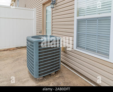 Horizontal shot of an air conditioning unit on the patio behind a condo. Stock Photo