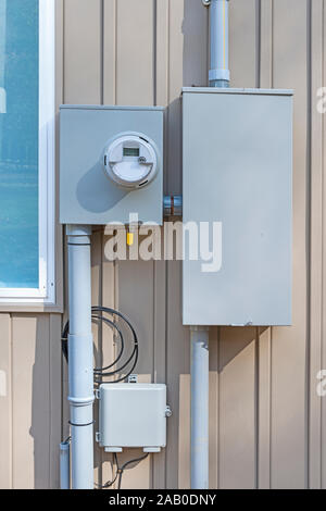 Vertical shot of a residential electric meter mounted on a wall. Stock Photo