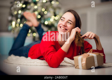 Low below angle view photo of charming cute beautiful attractive girl with a gift wearing jeans and red sweater Stock Photo