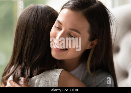 Mom cuddling daughter enjoy moment of tenderness feeling love Stock Photo
