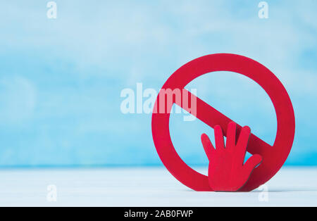 Red forbidden sign and hand  on blue background. Stock Photo