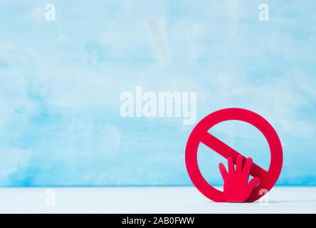 Red forbidden sign and hand  on blue background. Stock Photo