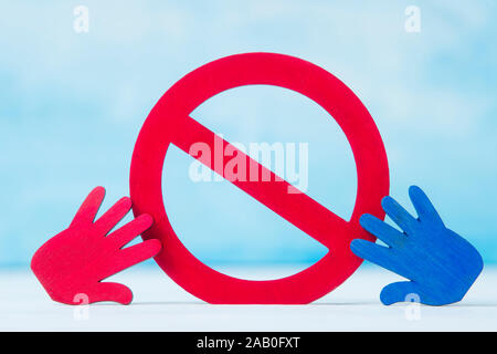 Red forbidden sign and hand  on blue background. Stock Photo