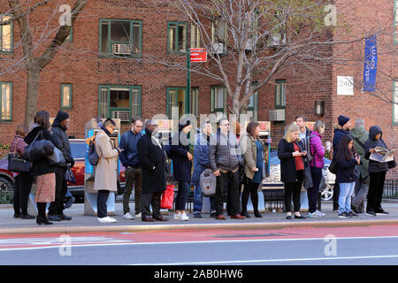 People waiting at a bus stop on the East Side of Manhattan at the tail end of the morning rush hour, New York, NY (November 21, 2019) Stock Photo