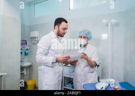 Young and senior chemists working together and looking at a test tube in a clinical laboratory Stock Photo