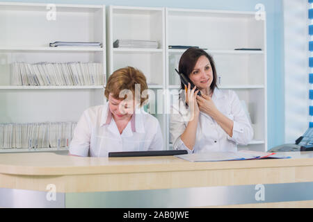 Two smiling nurses working at hospital reception desk Stock Photo