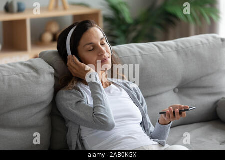 Woman wearing headphones enjoy music on smartphone Stock Photo