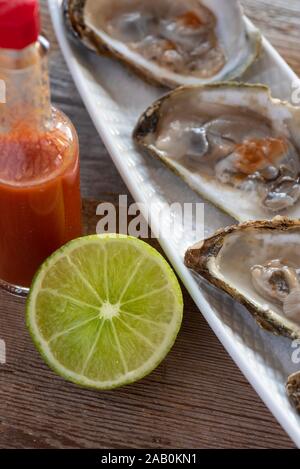 Oysters with lime and hot sauce. Stock Photo