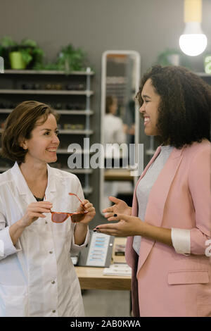 Two happy females - client and clinician - discussing new collection of eyewear Stock Photo