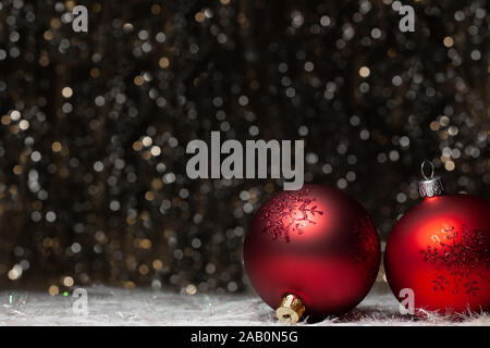 Christmas decorations composition view of two red evening balls with red glitter snowflakes on it of the right site on dark background with silver and Stock Photo