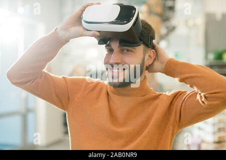 Happy young man looking at you with smile while taking off vr headset Stock Photo