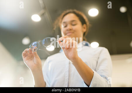 Hands of young contemporary mixed-race female holding pair of new eyeglasses Stock Photo