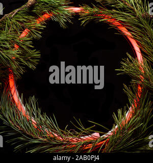 Christmas round frame made by neon and winter things on black background. Stock Photo