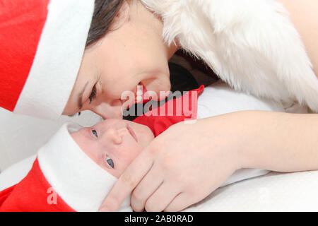 Photo of the Happy mother with male baby wearing christmas hats Stock Photo