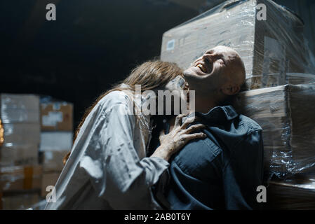 Female zombie bites a man in the neck, death trap Stock Photo