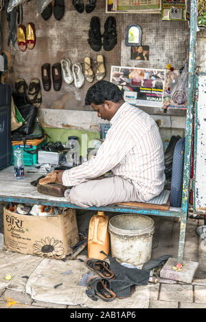 Bangalore, India, June 2018, streets of Bengaluru city, Hindu Indian shoemaker in street workshop repairing shoes and other leather items like bags Stock Photo