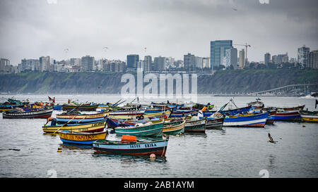 Lima, Peru - Nov 17, 2019: Fishing boats in Chorrillos harbour against the backdrop of the commercial Miraflores district Stock Photo