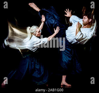 two budokas fighters man and woman practicing Aikido studio shot isolated on black background Stock Photo