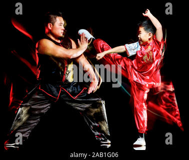 Two young Chinese kung fu students in bright orange robes practice ...