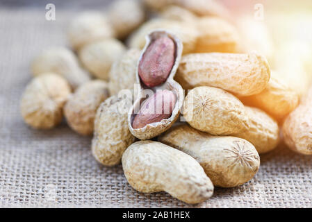 Roasted peanuts on a wooden bowl and sack background / Peanut in shells for food or snack Stock Photo
