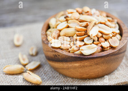 Roasted peanuts on a wooden bowl and sack background / salted peanuts as a food or snack Stock Photo