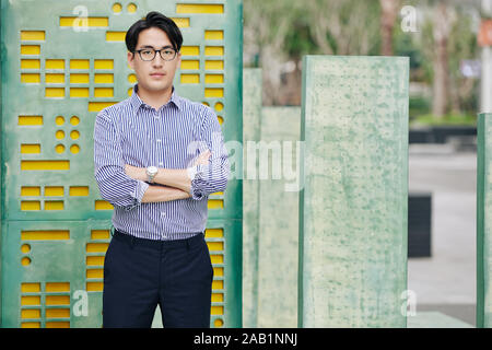 Portrait of young Asian software developer standing in the street and looking at camera Stock Photo