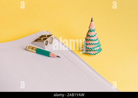 Creative christmas tree. Diary, pencil, shavings and sharpener on a yellow background. Christmas concept in office. Selective focus. Close up. Stock Photo