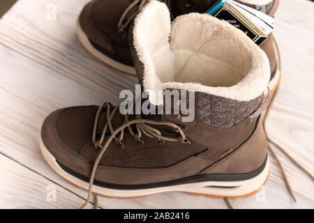 ladies or women winter boots, new brown unisex leather winter shoes on light wooden background. Stock Photo