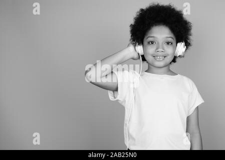 Young cute African girl with Afro hair listening to music in black and white Stock Photo