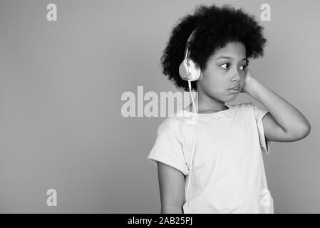 Young cute African girl with Afro hair listening to music in black and white Stock Photo