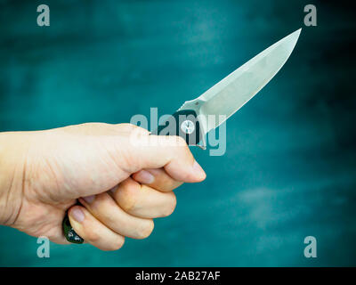 Hand holds pocket / folding / utility / knife on dark background Stock Photo